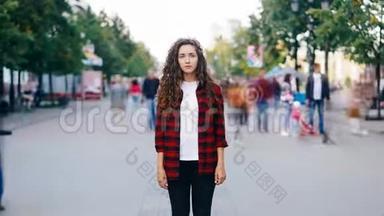 放大了站在步行街上的迷人的年轻女士的延时，直着脸看着镜头